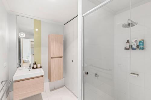 a white bathroom with a sink and a shower at Lovely Living in Lovely Banks