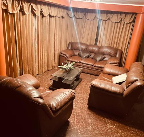 a living room with two leather couches and a table at Hostal El Rancho in Huancayo