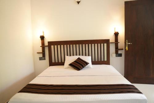 a bed with a wooden headboard and a pillow on it at Ali Adi Eco Lodge in Sigiriya