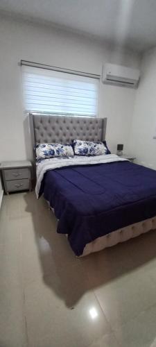 una camera da letto con un letto con un piumone blu e una finestra di Virginia III Condominium 302 a San Pedro de Macorís