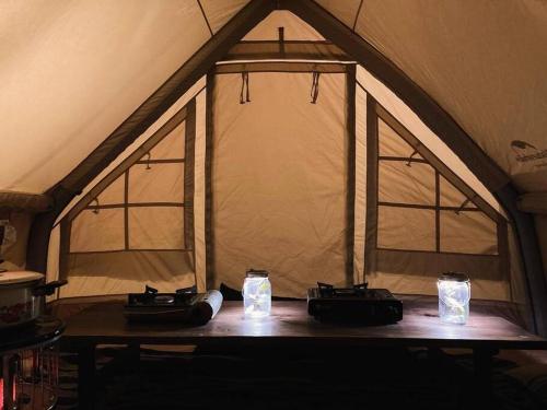 a wooden table with two candles in a tent at Lemon tree hotel in Higashiura