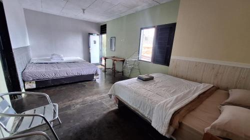 a room with two beds and chairs in it at Smiley's Homestay in Berastagi