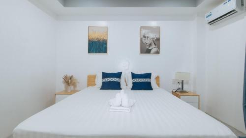 a bedroom with a large white bed with blue pillows at ADC Resort and Hotel Apalit Pampanga in Apalit