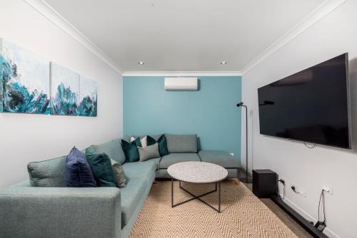 a living room with a couch and a flat screen tv at Woodlands Sunsets Soldiers Point - Whole Property in Soldiers Point