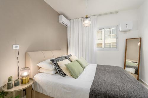 a bedroom with a bed with pillows and a mirror at Unique Mini Penthouse In The Heart Of Jerusalem in Jerusalem