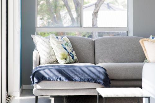 a couch in a living room with a window at Woodlands Sunsets Soldiers Point - Whole Property in Soldiers Point