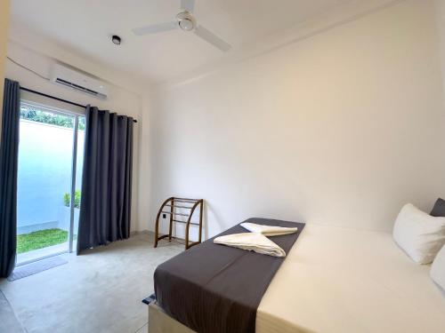 a bedroom with a bed and a sliding glass door at Moringa Mirissa in Mirissa