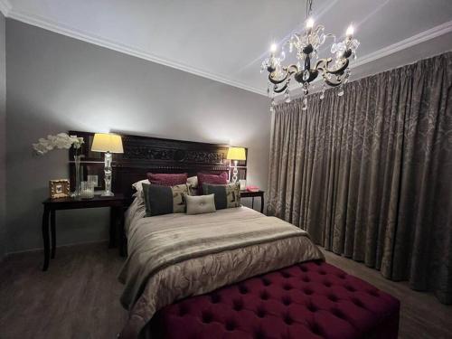 a bedroom with a large bed and a chandelier at Hillside Manor in Dalmada AH