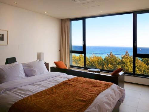 a bedroom with a bed and a view of the ocean at Maple Beach Golf & Resort in Gangneung