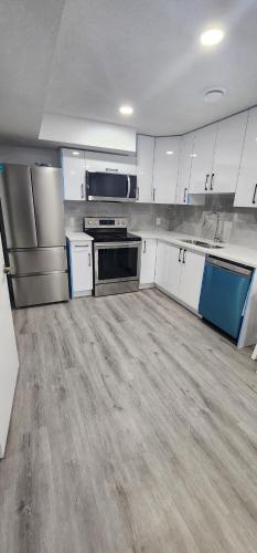 a large kitchen with white cabinets and appliances at Cozy One bedroom BSMT Apartment in Edmonton