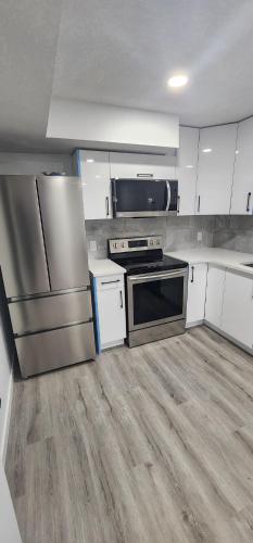 a kitchen with stainless steel appliances and white cabinets at Cozy One bedroom BSMT Apartment in Edmonton