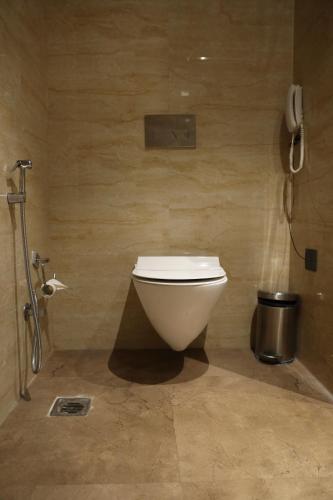 a bathroom with a toilet and a phone on the wall at HOTEL LE SEASONS PARK in Greater Noida