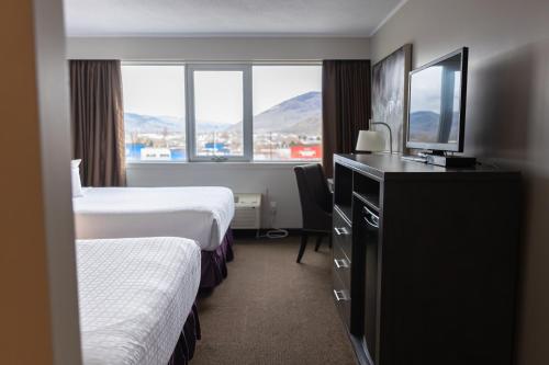 una camera d'albergo con 2 letti e una scrivania di The Thompson Hotel a Kamloops