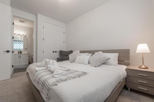 a white bedroom with a large bed and a lamp at Room 2 of Lovely home, Montgomery downtown Calgary in Calgary