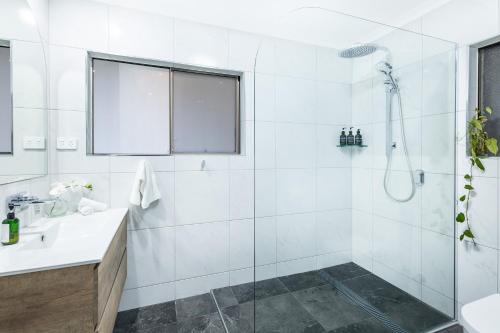 baño blanco con ducha y lavamanos en Tranquil 3BR King Home, Pool, BBQ en Trinity Beach