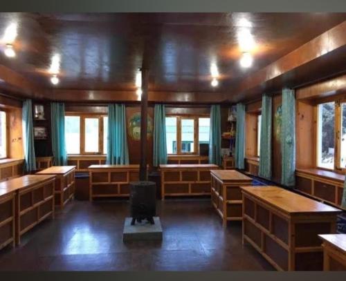 a room with wooden tables and benches and windows at White lotus inn in Pangboche