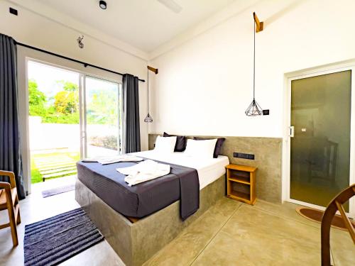 a bedroom with a bed and a large window at Moringa Mirissa in Mirissa