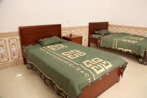 a bedroom with two beds with green comforters at Khu du Lịch Trải nghiệm Gốm Phù Lãng in Bắc Ninh