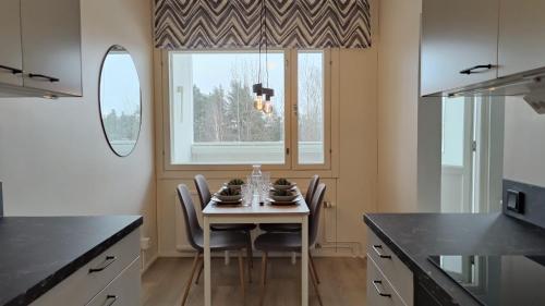 uma cozinha com uma mesa com cadeiras e uma janela em Green Getaway - near Helsinki Vantaa Airport, top-floor, free parking & wifi em Vantaa