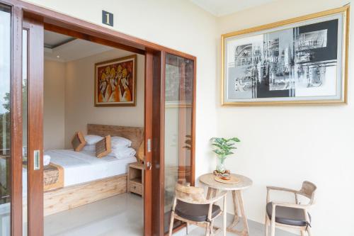 a bedroom with a bed and a table and chairs at Oka Suite Sebatu Ubud in Tampaksiring