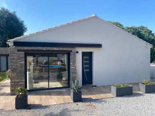 a white garage with glass doors and potted plants at Villa charme et tradition in Poulx