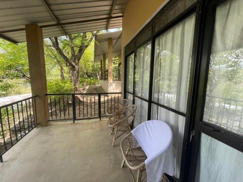 porche con 2 sillas y balcón con ventanas en Tamarind Gardens, en Digana