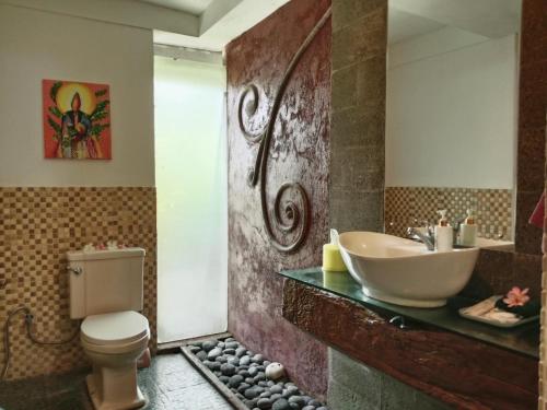 a bathroom with a sink and a toilet at Javanese Joglo House by Malathi Ubud in Ubud