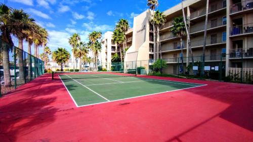 a tennis court in front of a building with palm trees at Edgewater 507 Condominium Condo in South Padre Island