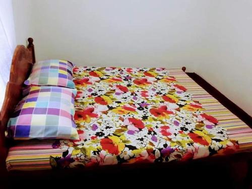 a bed with a floral blanket and pillows on it at Black And White Elkaduwa Guest House in Elkaduwa