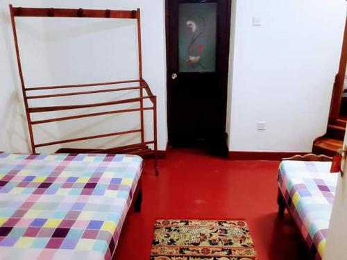 a room with two beds and a door with a rug at Black And White Elkaduwa Guest House in Elkaduwa