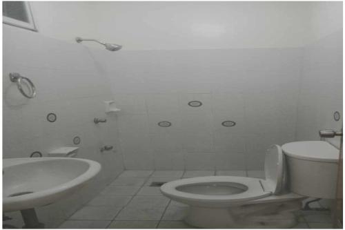 a white bathroom with a toilet and a sink at Villa Celine Laguna in Masaya