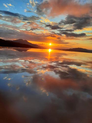 a reflection of the sun in the water at sunset at Hotel Chail Residency in Chail