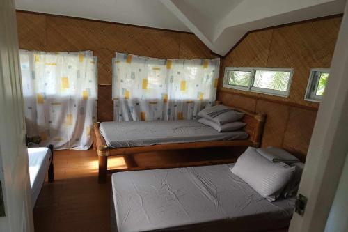 a small room with two beds and two windows at Villa Celine Laguna in Masaya