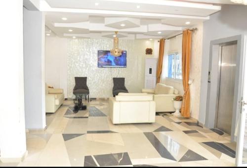 sala de estar con muebles blancos y suelo a cuadros en Explorez le charme et élégance de MMEWEL HÔTEL en Douala