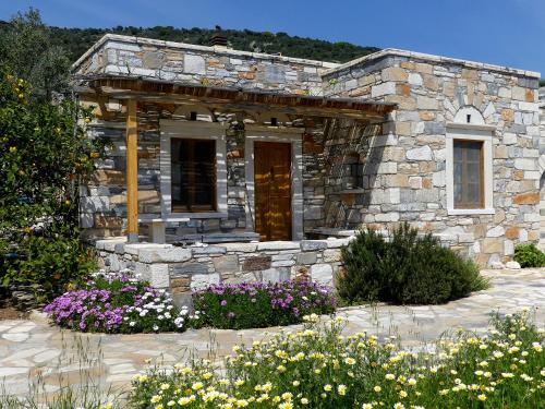 a stone house with flowers in front of it at Traditional stone-built cottages Azalas in Moutsouna Naxos