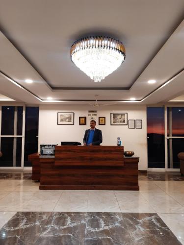 a man standing at a reception desk in a lobby at Hotel Chail Residency in Chail