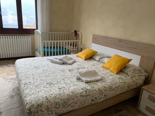 ein Schlafzimmer mit einem Bett mit zwei Kissen und einem Kinderbett in der Unterkunft Gere house in Lezzeno