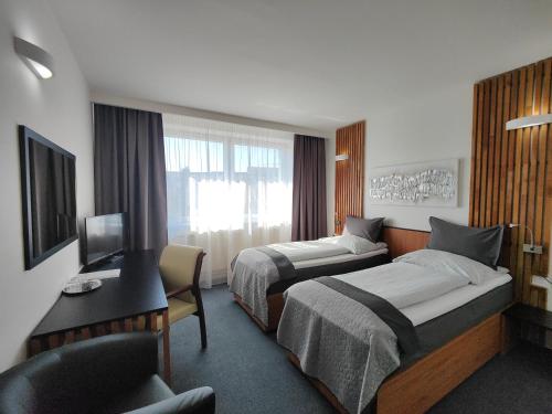 um quarto de hotel com duas camas e uma secretária em Hotel P7 em Lučenec