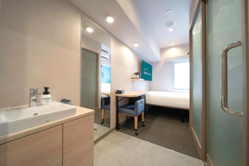 a bathroom with a sink and a desk and a bed at Hop Inn Tokyo Ueno in Tokyo