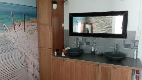uma casa de banho com dois lavatórios e uma televisão na parede em Maison de campagne em Puycornet