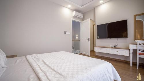 a white bedroom with a large bed and a flat screen tv at JB. Nguyễn Villa NovaWorld Phan Thiết in Phan Thiet
