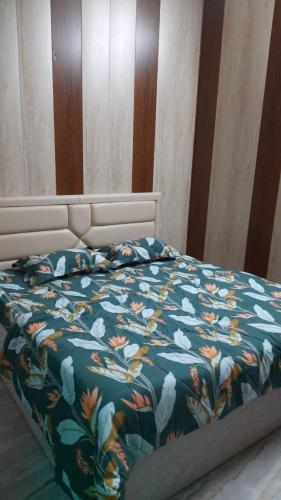Preet Home Stay في فاراناسي: سرير مع لحاف أزرق عليه زهور