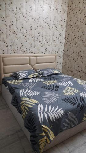 Preet Home Stay في فاراناسي: سرير مع لحاف ووسائد زرقاء عليه