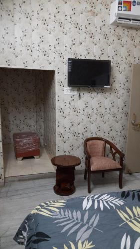 Preet Home Stay في فاراناسي: غرفة بها تلفزيون وكرسي وطاولة