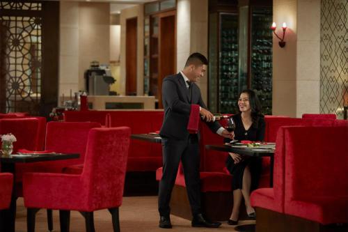 a man and a woman sitting at a table in a restaurant at Shangri-La Jakarta in Jakarta