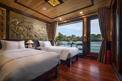two beds in a room with a view of the water at V'Spirit Cruise in Ha Long