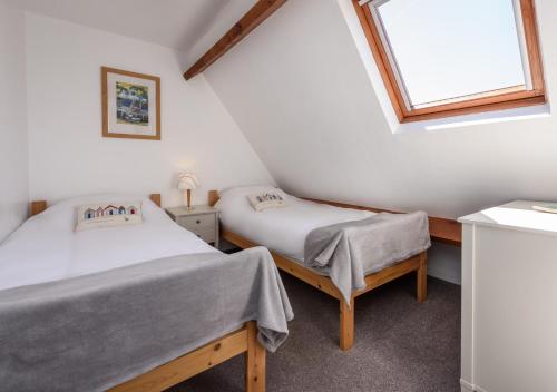 two beds in a small room with a window at Tonnau in Abersoch