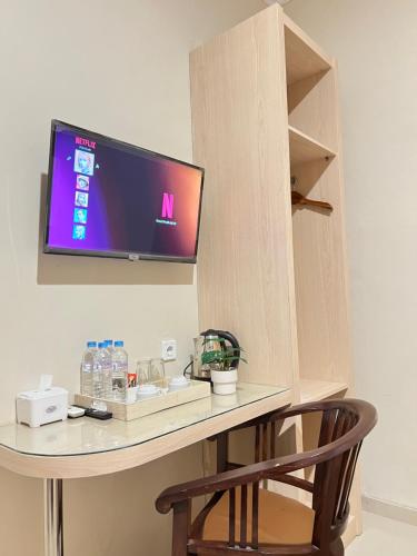 a desk with a tv on a wall with a chair at Ayuri Hotel Malioboro in Sentool
