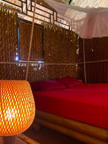 a bedroom with a red bed and a lamp at Hometravel Mekong Can Tho in Can Tho