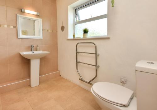 a bathroom with a toilet and a sink and a window at Y Stabl in Abersoch